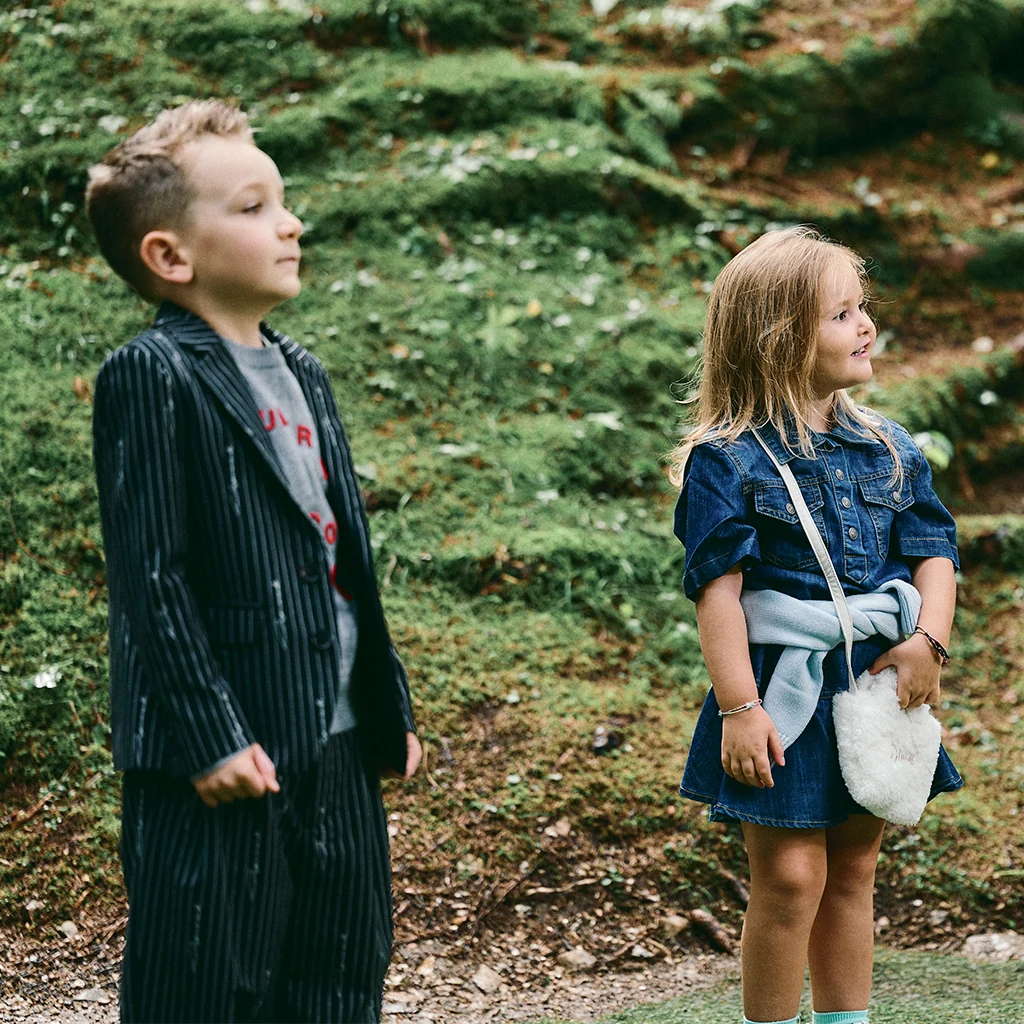 A Baby Boy and a Baby Girls, deep in the woods, wearing stylish outfits.