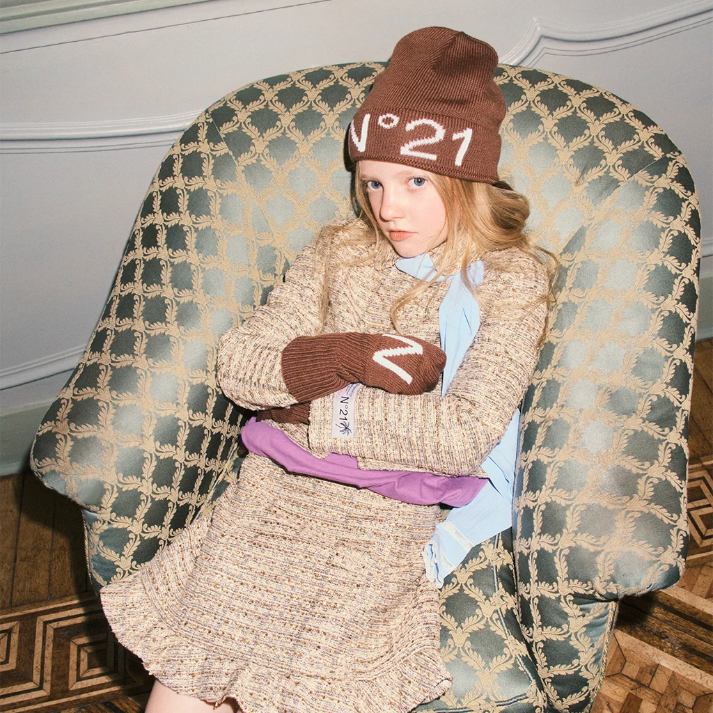 A girl sitting on a couch, wearing a warm and stylish outfit by N°21