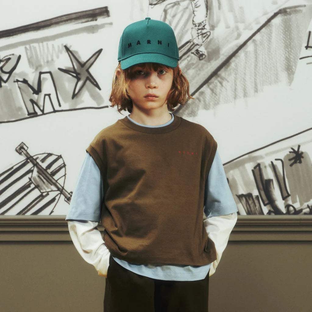 Boy wearing a comfortable and colorful outfit by Marni, against a wall full of doodles