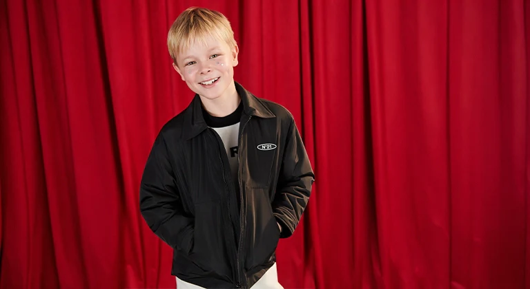 Jackets category - A boy smiling with a black jacket and a red background