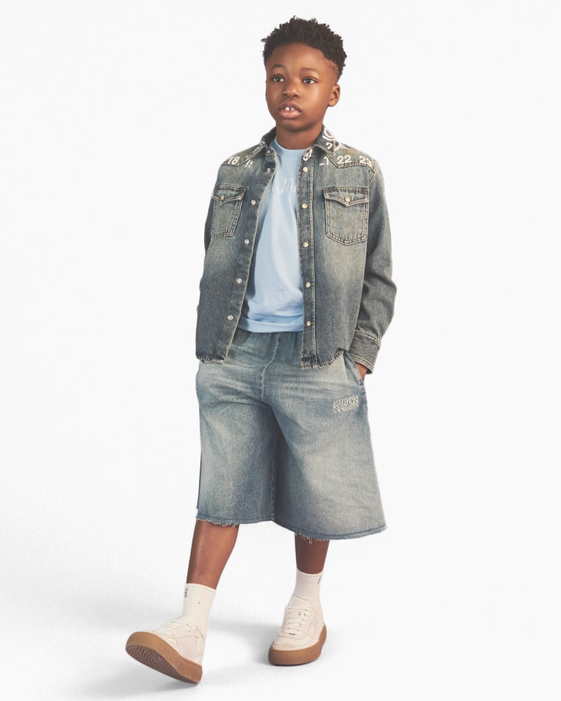 Child wearing a denim jacket and shorts on a white background